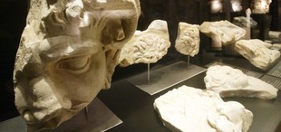 Peces que integren l'exposició. A baix, detall d'un monument funerari decorat amb una roseta de vuit pètals i, a la dreta, el director del MNAT.  Foto: J. FERNÀNDEZ.